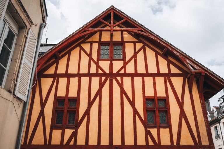 This is a red and yellow half timbered framed building at 9-11 Rue Jean Jacques Rousseau in Dijon. It's the front of the building and it has three windows.