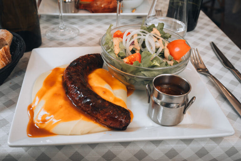 Aligot topped with a sausage and a side salad. The food is one of the best things about France.