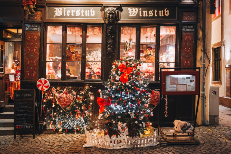 Au Vieux Strasbourg Winstub on Rue du Maroquin decorated with lights, a Christmas tree, and ornaments during the Christmas market in Strasbourg at night.