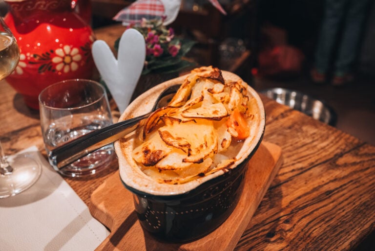 Baeckeoffe, a casserole made with meat and potatoes, from Caveau du Vigneron in Turckheim. There is a spoon and a fork sticking out of the clay pot containing the casserole. 