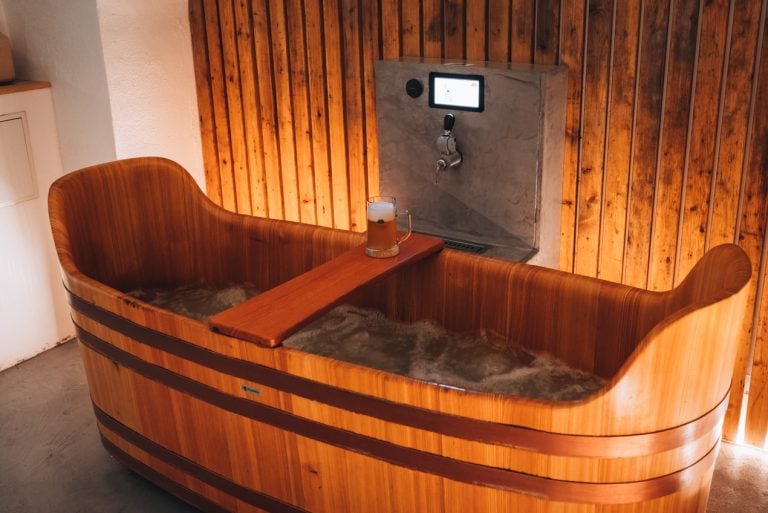 This is the beer spa. It's a wooden hot tub with bubbling water. There is a glass of beer and a tap of beer.