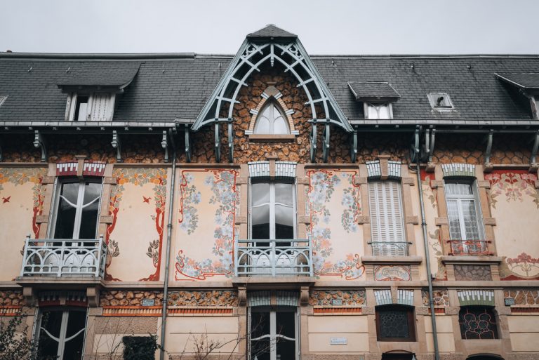 This is the top of one of the buildings alone Rue Félix Faure in Nancy. It has colorful flowery designs around the windows.