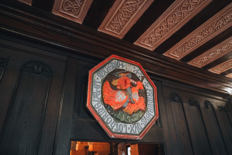 This is the Lorraine Room. This is the ceiling that is made of wooden panels. Then above the doorway there is a shield  that shows a solider on a horse with a sword.
