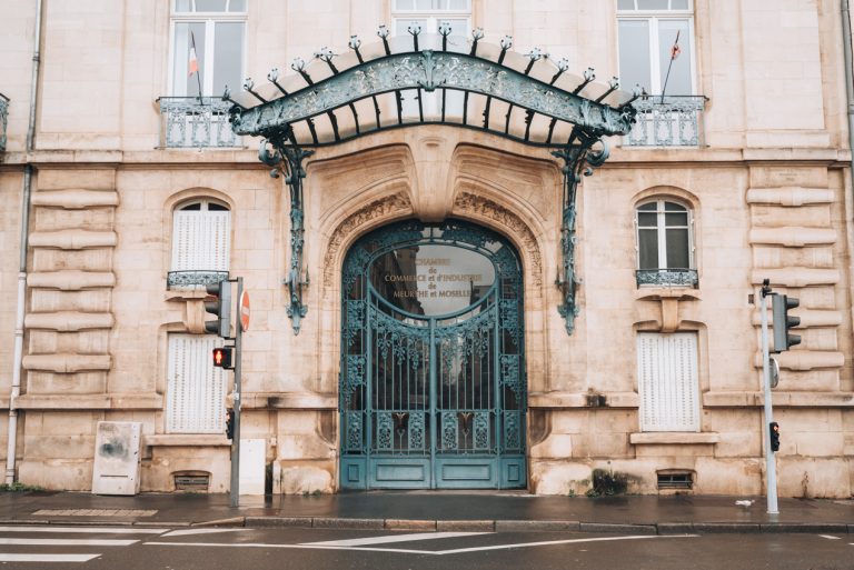 This is the entrance of Chambre de Commerce et d'Industrie in Nancy. The door and overhang are made of iron and decorated with leaves and flowers made of iron.
