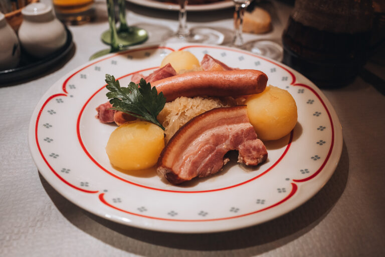 A plate Choucroute Garnie from the Gurtlerhoft Restaurant in Strasbourg. It consists of sauerkraut, potatoes, pork, and parsley.
