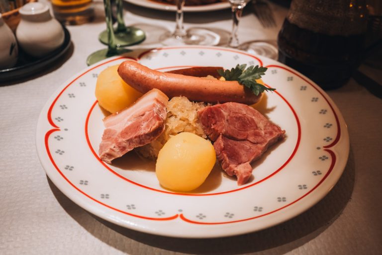 This is Choucroute garnie. It's a traditional dish from eastern France. It consists of sauerkraut topped with different types of pork and two potatoes.