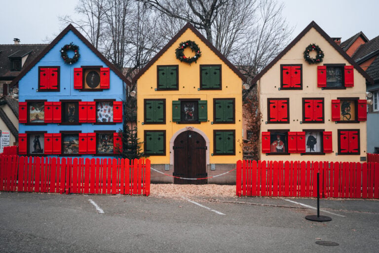 Three wooden houses with Christmas decorations at the Christmas market in Turckheim.