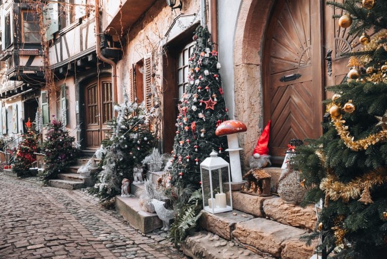 This is a row of Christmas trees decorated with lights and ornaments on Rue du Rempart in Eguisheim.