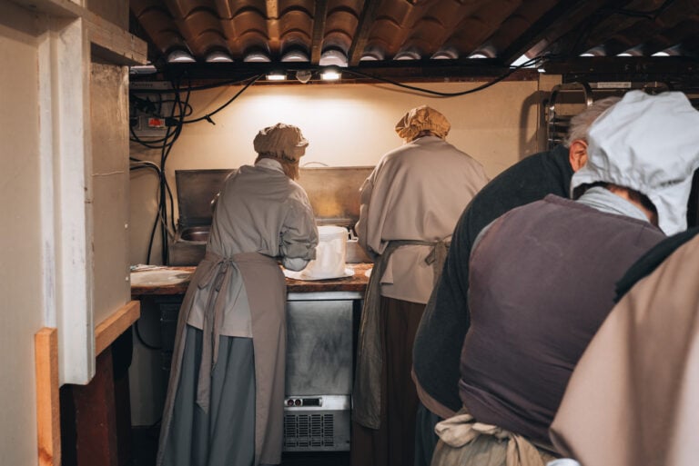 Cooks working in the kitchen and preparing my tart flambée from scratch. This was one of my favorite highlights of this Christmas market.