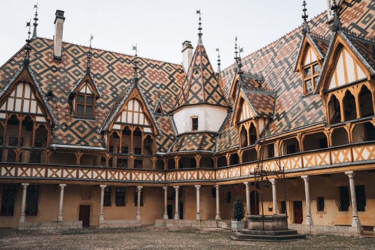 This is the courtyard at Hôtel-Dieu Museum Hospices de Beaune. It's a large timber framed building with a colorful tiled roof.
