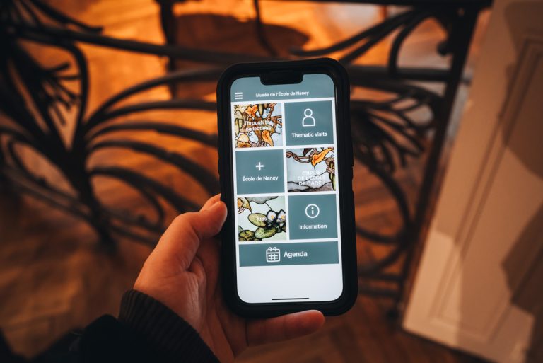 This is the École de Nancy Museum App. I am holding my phone and the screen shows the different tours you can do at the museum.