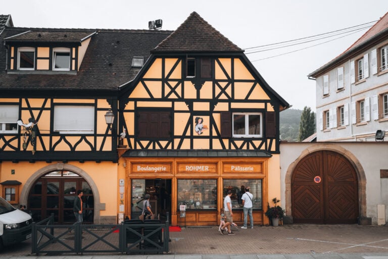 Entrance to Rohmer Bakery in Rosheim. The bakery storefront sits on a quiet cobblestone street with wooden beams and windowsills.