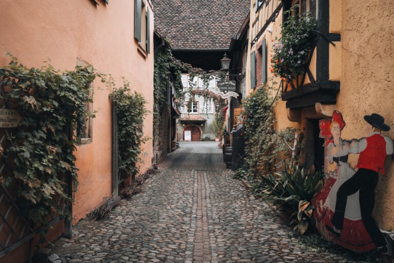 A cobblestone road lined with hanging vines leads to the entrance of the winery Domaine François Baur in Turckheim.