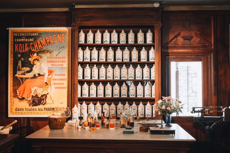 This is an exhibit at the Musée de la Vie Bourguigonne in Dijon. It shows the inside of a pharmacy during the 19th and 20th centuries. There are bottles of medicine on the wall and a counter with they can be purchased.