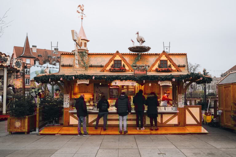 This is a food stall at Place Rapp in Colmar at Christmas. It's selling traditional Alsatian specialties and there are people buying food.