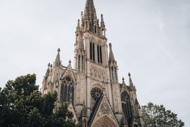 This is the of Basilica of Saint Epvre in Nancy France. There is the steeple and stained glass windows. Then, the outside is decorated with intricate stone sculptures.