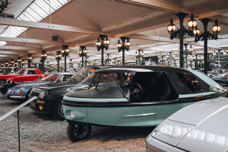 This is a futuristic looking car at at the Musée National de l'Automobile in Mulhouse. It has one front whell and dome shaped top with large doors.