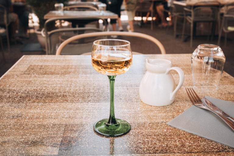 Glass of white Alsace wine served at Domaine Blanck in Obernai in a traditional tall green stemmed wine glass. Wine tasting at local wineries is another memorable experience for visitors.