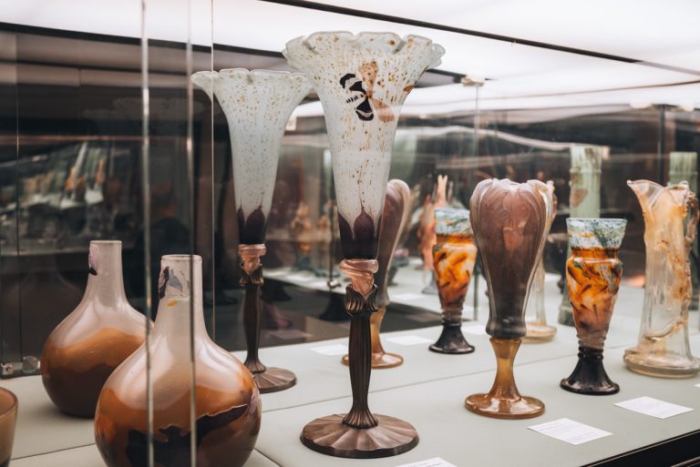 This is a glass-work exhibit by Émile Gallé at the Musée de l'École de Nancy. There are five different vases all with different flowery designs.