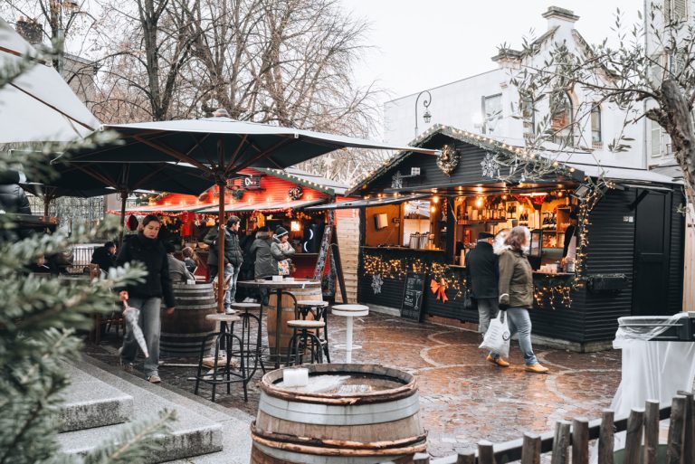 This is the Gourmet Market in Place Vaudémont in Nancy on Saint Nicolas Day. There are huts selling food and people are walking around.