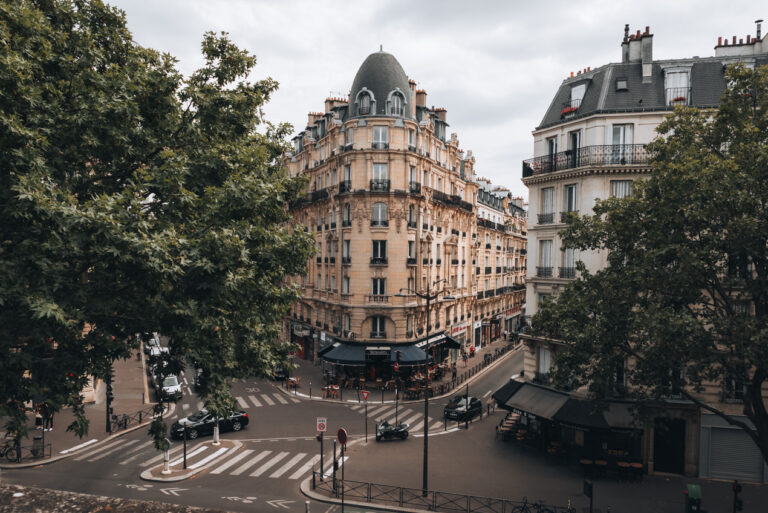 Cream stone Haussmannian building surrounded by trees in Paris as see La Coulée Verte. This is one of the most loved types of architecture.
