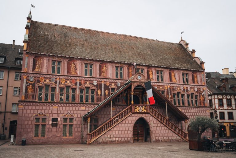This is Hôtel de Ville in Mulhouse. It's painted as an optical illusion and the statues look real. Then in the front there is a French flag.