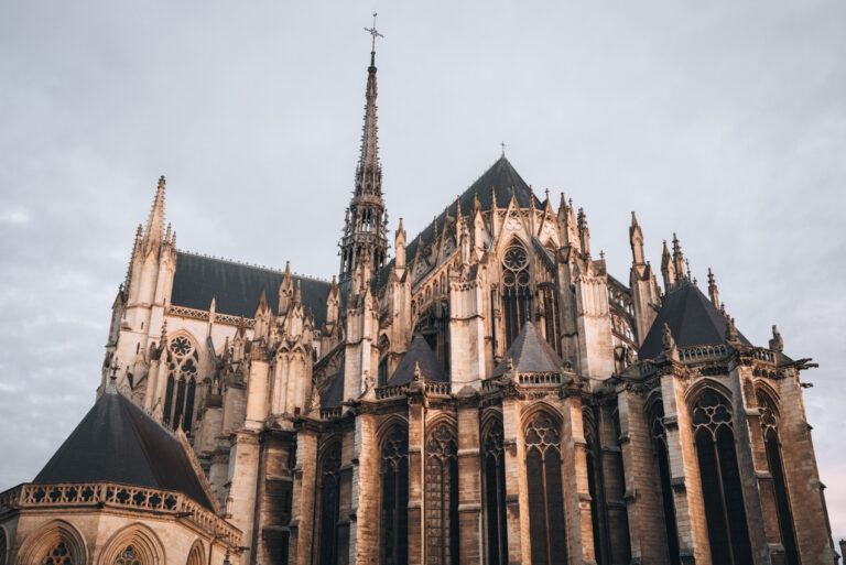 The spire of the Amiens Cathedral towers over the statues on the backside at sunrise. It was this church that made me wonder how many churches are there in France.