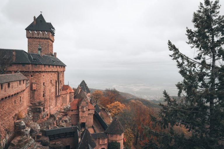 This is a view of the Haut Koenigsbourg Castle in Alsace from the upper terrace. There is the ride side of the castle with the main tower then in the distance there is the valley below.