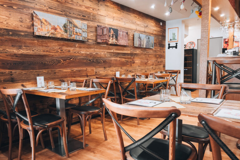 Wooden chairs and tables in a small room at La Soi in Colmar.
