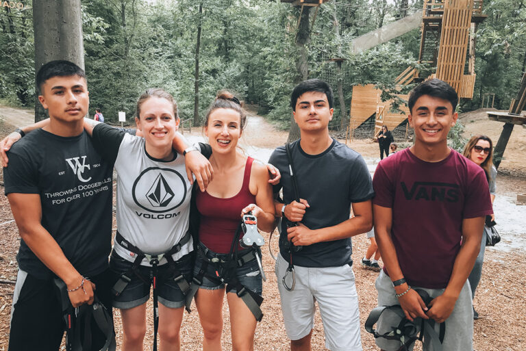 Jen with her aunt and cousins at AccroCamp Adventure Park surrounded by tall trees on a sunny summer day in Paris. The treetop obstacle course is a fun outdoor activity for families.