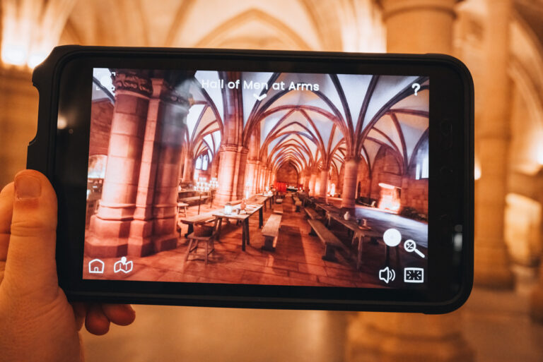 Jen holding a digital guide inside the Conciergerie while exploring the historic Gothic halls of the former royal palace in Paris. Touring this landmark is one of the fascinating historical attractions in Paris.