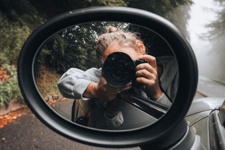 Jen in her rental car taking a photo of herself in the driver's side mirror.