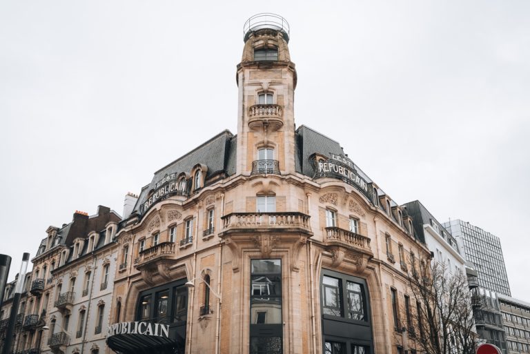This is the front of the L'Est Républicain in Nancy. It's a large square building with a tall tower in the middle. The decorations along the windows are flowers and leaves, which are typical of the art nouveau style.