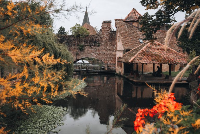This is the Lavoir du Bruch in Wissembourg. It's small place to wash clothes. There is the canal and a covered terrace with a person sitting on a bench.