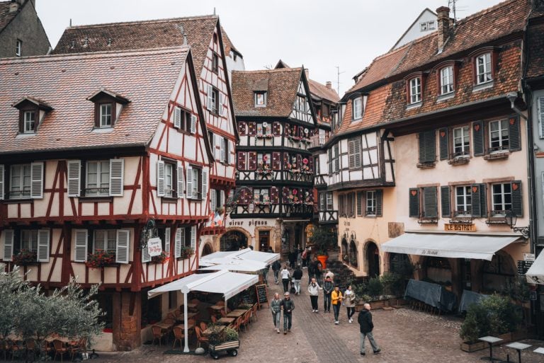 This is Le Fer Rouge on Rue des Marchands in Colmar. It's a red and white half-timbered house that sits along a cobbled street.