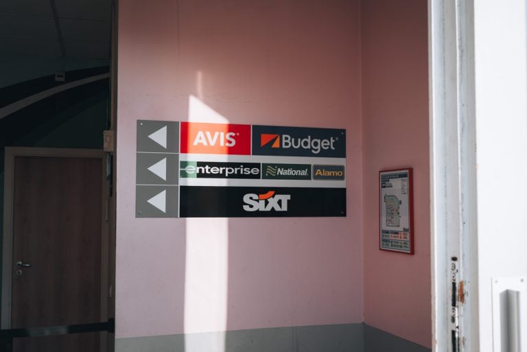 This is a list of the car rental companies at the train station in Strasbourg. It's a list of most of the companies on the wall with arrows pointing to their welcome desks.