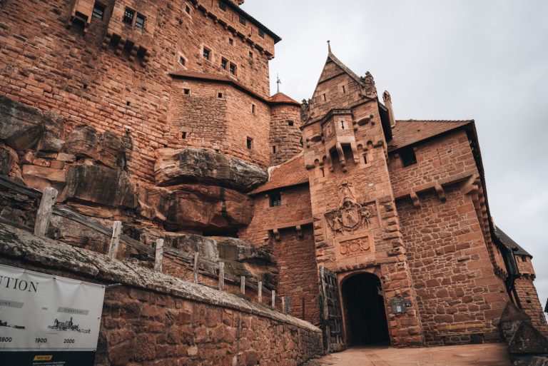 This is the main entrance of the the Haut Koenigsbourg Castle. It's made of stone. There is a small doorway with the coat of arms of Emperor Wilhelm II above it.