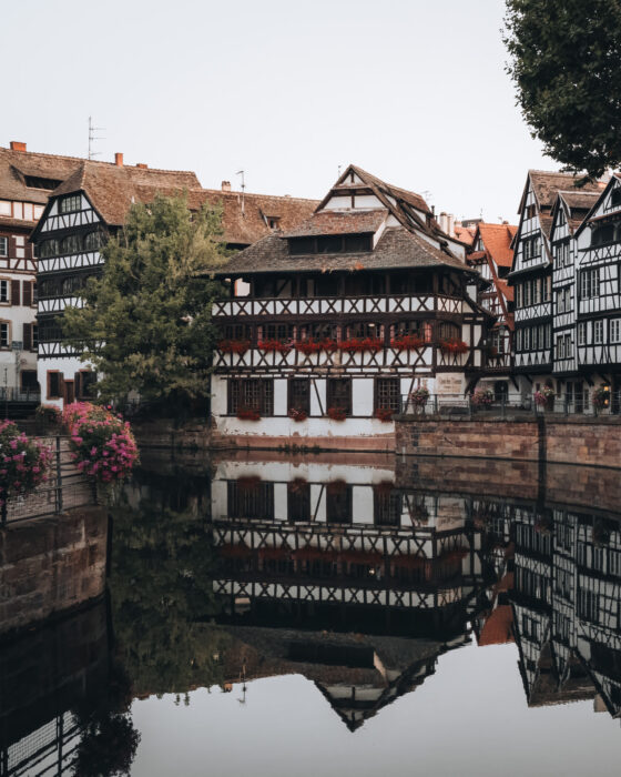 Early morning light illuminates the historic Maison des Tanneurs along the canal in Strasbourg’s Petite France district, with soft reflections shimmering on the water.