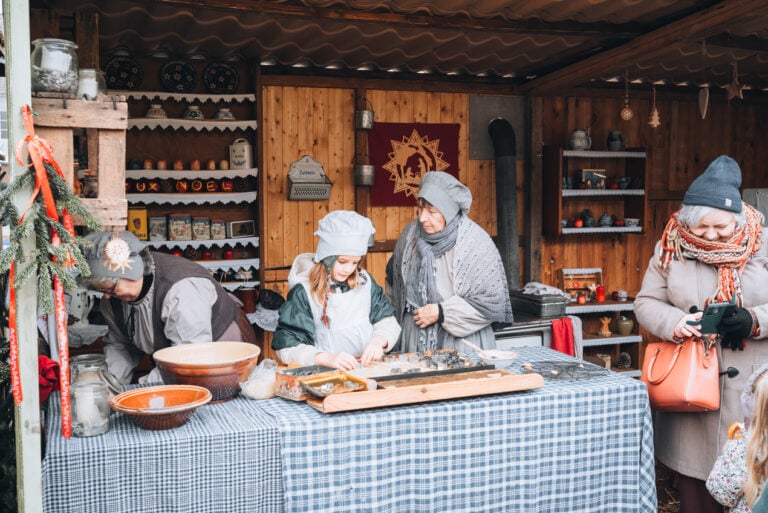 A young child and her grandmother are cutting dough in preparation for making Bredele at the Christmas market in the town of Neuf Brisach.