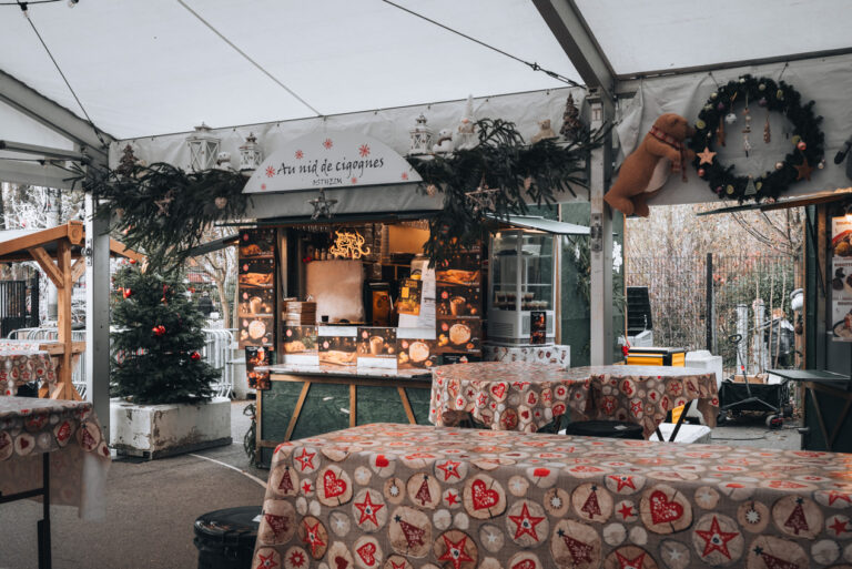 Marché Gourmande at the Christmas market in Colmar. Rows of tables are surrounded by food stands selling traditional dishes.