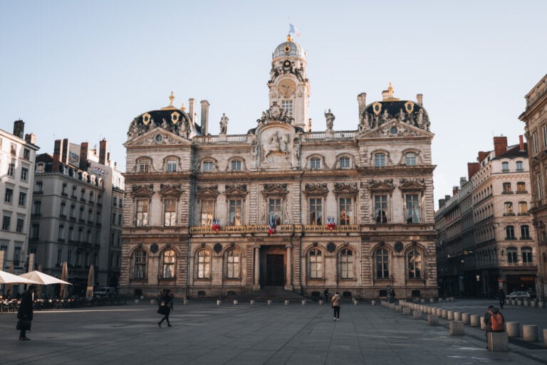 Place des Terreaux with the Hôtel de Ville in center frame. It's a quiet morning as commuters walk to work across the square. This is one of the many things to do in Lyon.