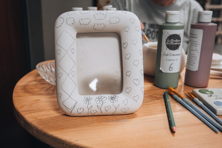 My picture frame with my pencil drawings at La Boutique des Bouleaux. The is the picture frame, a pencil, paint bottles, and paint brushes.