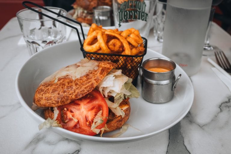 This is my giant gougère from La Brasserie des Loges in Dijon. It's a large pastry filled with chicken, tomatoes, and lettuce. There is a side of mustard and fries.