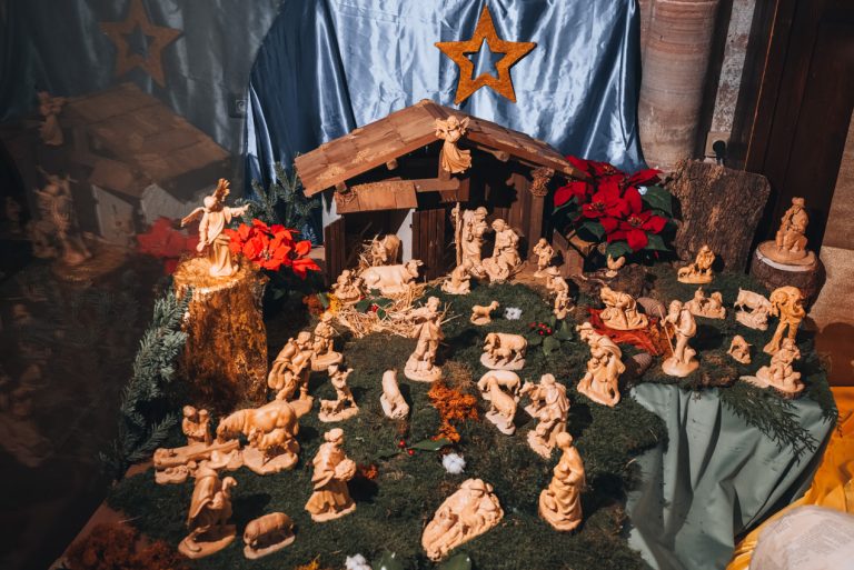 This is one of the nativity scenes at at the Saint Peter and Saint Paul Abbey in Wissembourg. There are wooden piece on a piece of fake grass and there is a star above the manger.