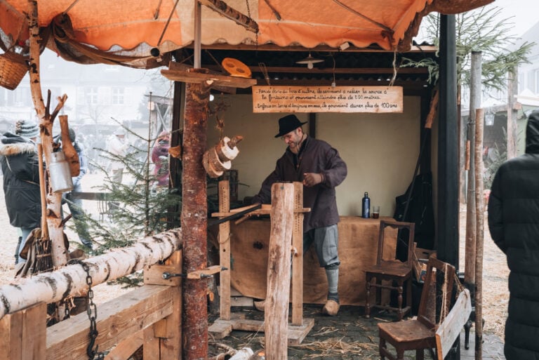 A carpenter chisels away at a log and prepares it to design a desk. This is one of the main locals who dress up at the Neuf Brisach Christmas market.