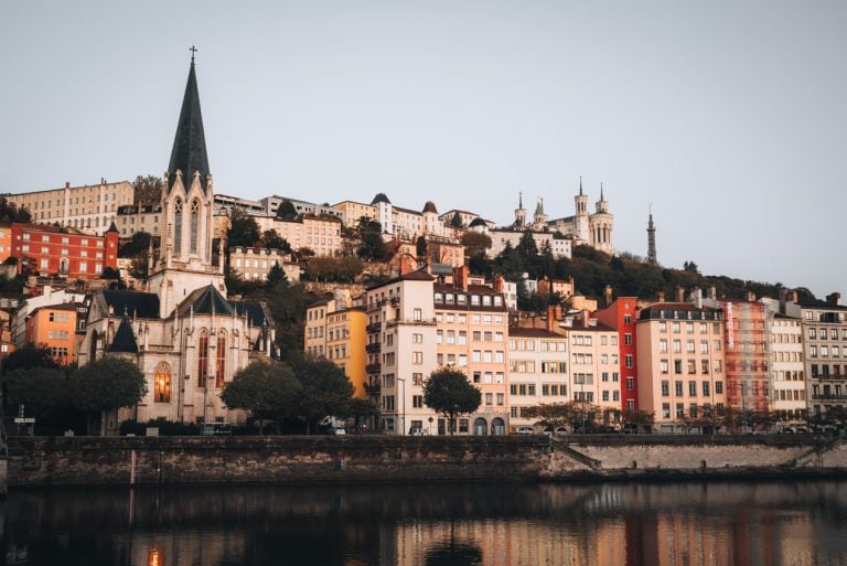 This is Lyon's Old Town at sunrise. There are colorful stone buildings lined along the Saone River.