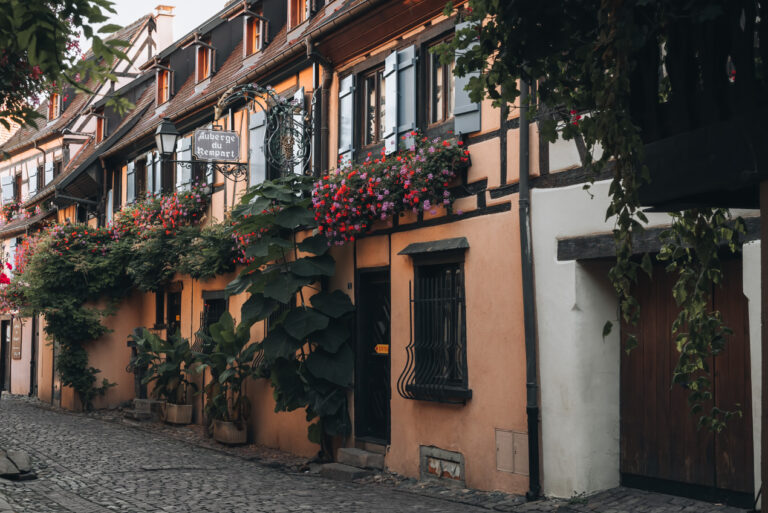 A cobbled street lined with an orange timbered building in Eguisheim. 