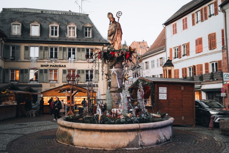 Fontaine Saint-Thiébaut decorated with wreaths and lights at Place Saint-Thiébaut in Thann at Christmas time.