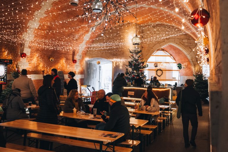 This is the Porte de la Craffe at Fêtes de Saint-Nicolas in Nancy. There Christmas decorations and lights, and people are eating and drinking a the tables.