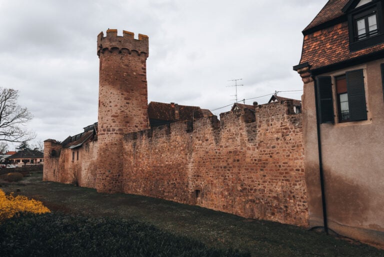 Section of Obernai’s historic ramparts featuring a tall stone defensive wall and a round lookout tower. The preserved fortifications can be seen along the short Ramparts Trail that circles part of the town.